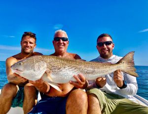 Three Men Holding Large Redfish